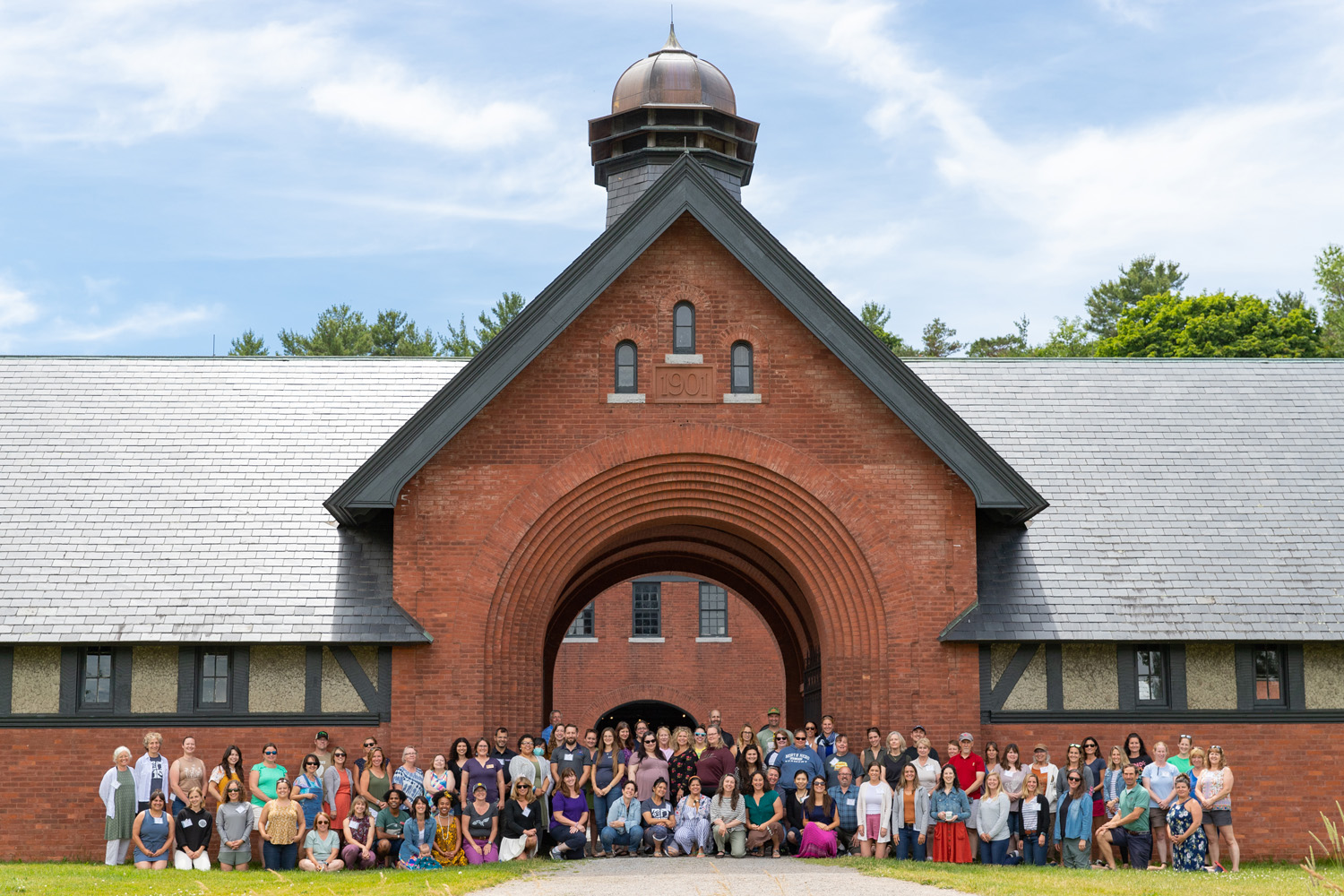 A large group of educators pose for a photo in front of the Coach Barn