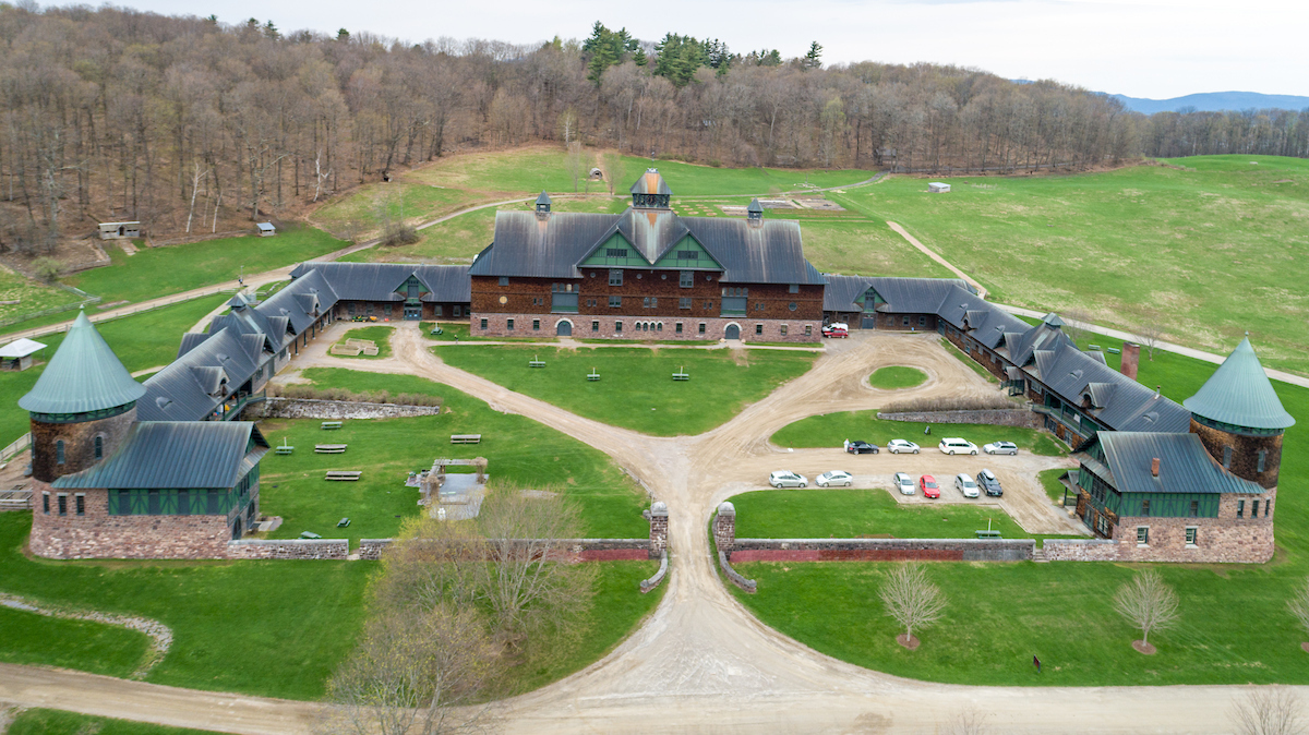 aerial of farm barn;  three sided building with open grass courtyard and stone wall in front