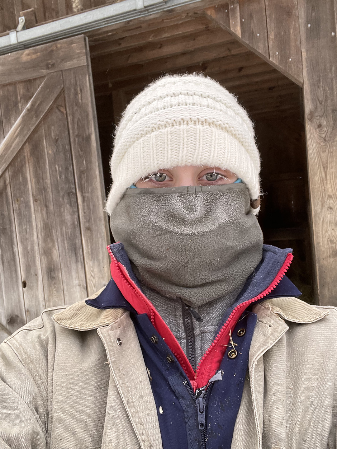 woman dressed for the cold: with a hat, scarf over her face, and frosted eyelashes