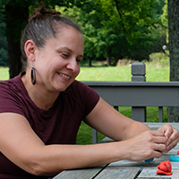 A portrait of a woman manipulating Play Doh on an outdoor table