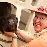 A portrait of a woman laughing with a small black cow