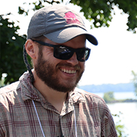 A portrait of a man in sunglasses smiling outdoors