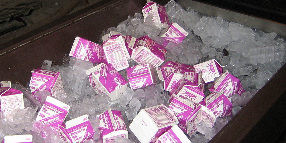 Small milk cartons sit on ice in a cooler