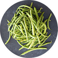 looking down on a pile of green beans on top of gray slate