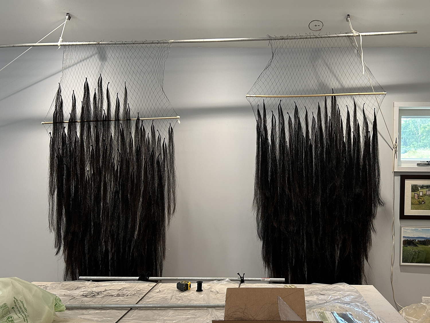 strips of horsetail hair attached to a nylon web hanging from an art studio ceiling
