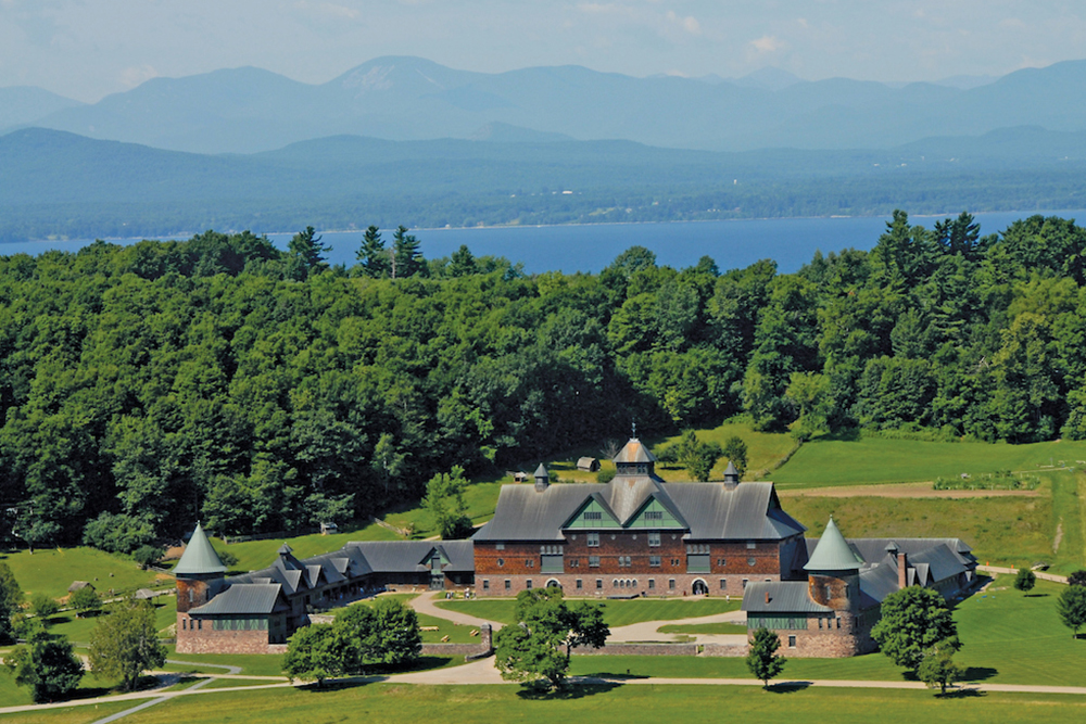 looking down on historic Farm Barn with forest, lake, mountains, and blue sky in background