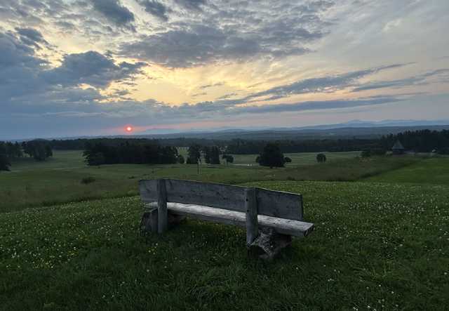 sunrise over green mountains with bench in foreground