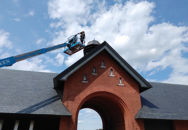 coach barn arched courtyard door with person working on roof from a lift