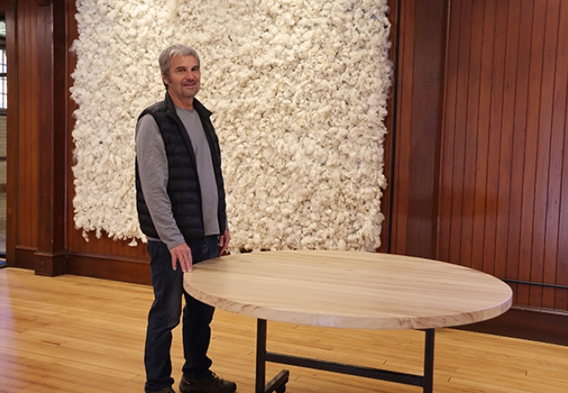man in black vest standing beside round wooden table