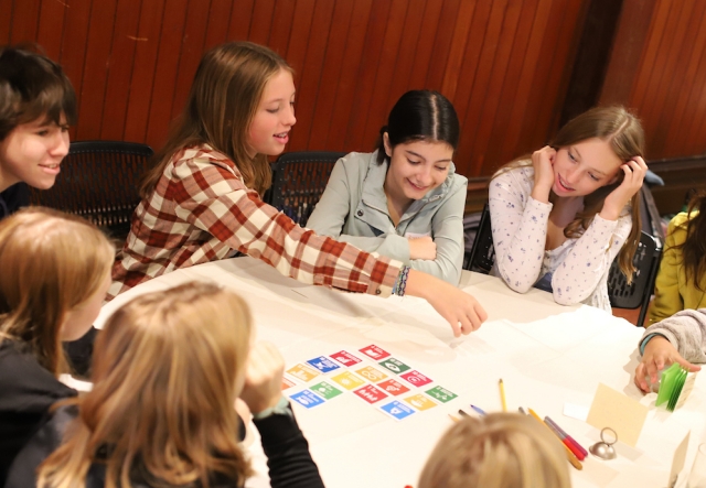 young teens seated at a white round table.