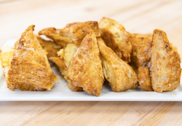 A plate of freshly baked cheddar scones is displayed on a  white plate.