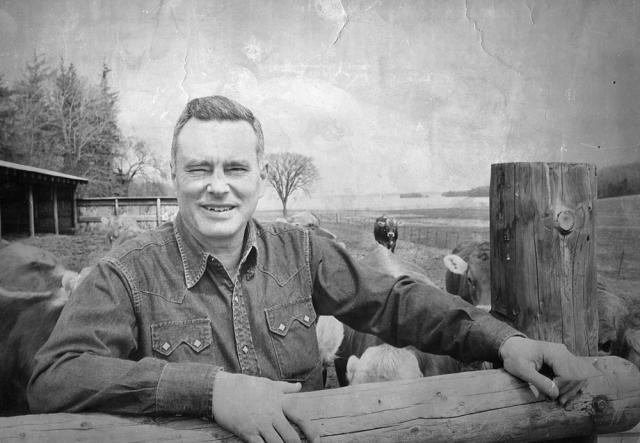 Derick Webb outside with arms draped over fence railing