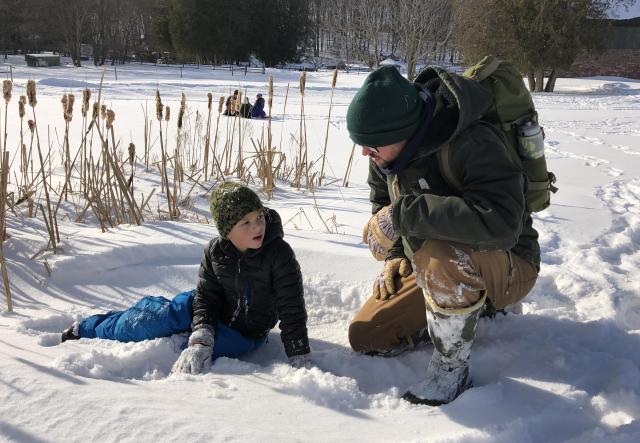 a child and adult explore the snowy landscape