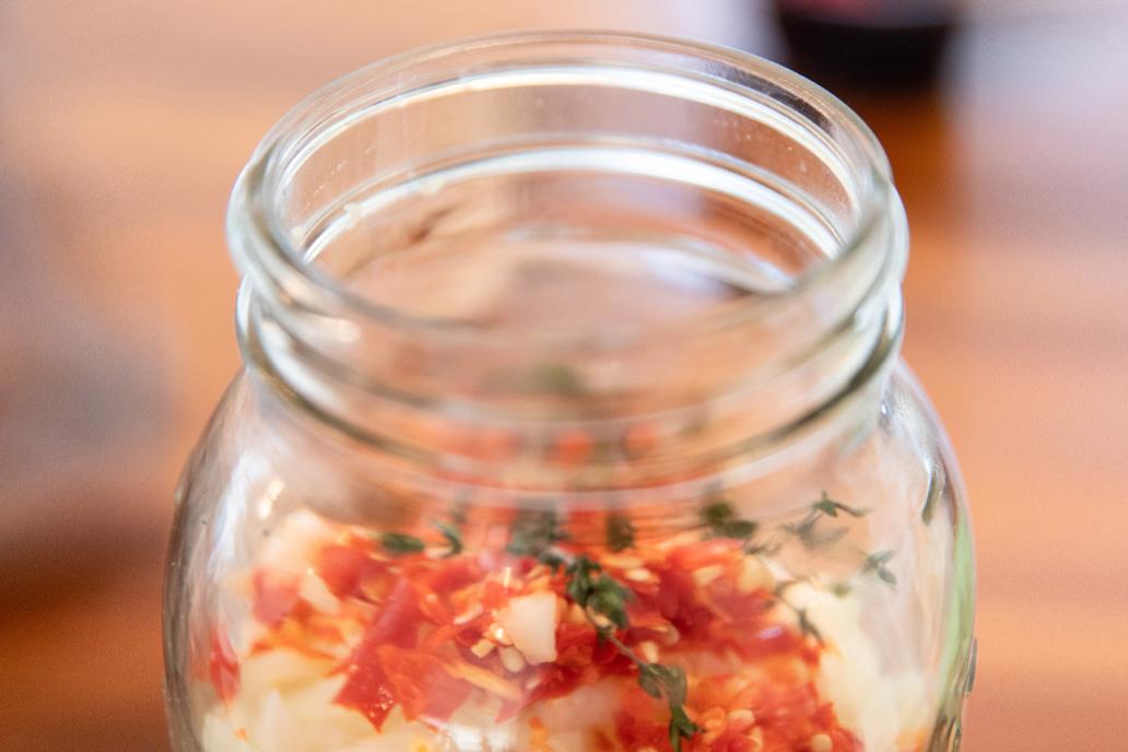 A glass jar filled with fire cider ingredients.