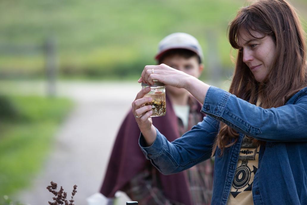 A participant hand tightens a ring lid onto a glass jar filled with chopped up roots and a clear liquid – the makings of a bitter tonic.