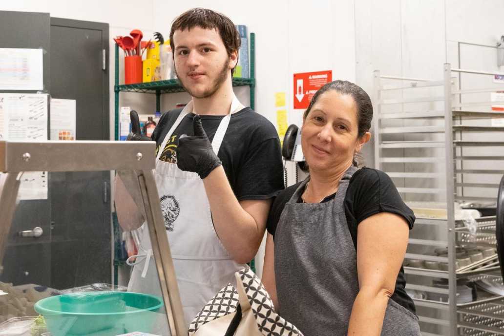 District Manager of Food Programs Jennifer Hutchinson works with a student in the kitchen preparing for the day’s events.