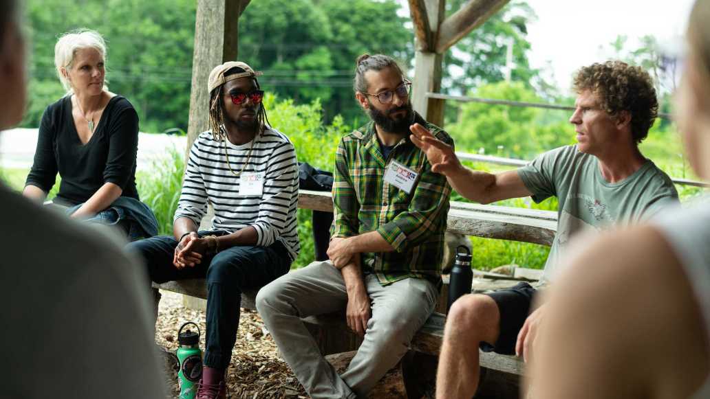 Educators sit under an outdoor pavilion in a garden