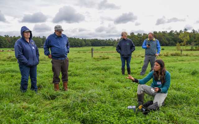 Farm-based educators stand in a green pasture.