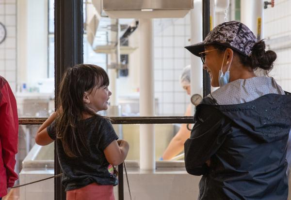 adult and child look through window to see cheese being made