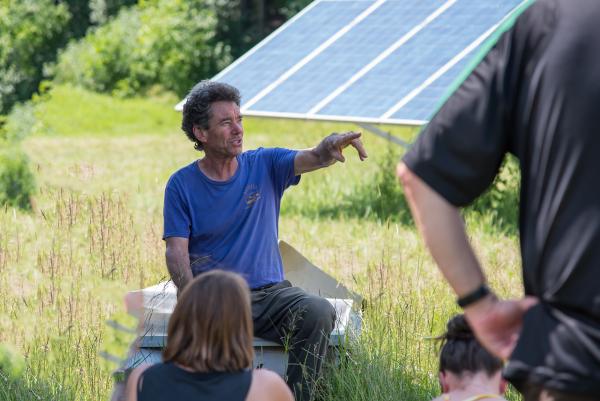 Marshall Webb sitting near solar panels pointing