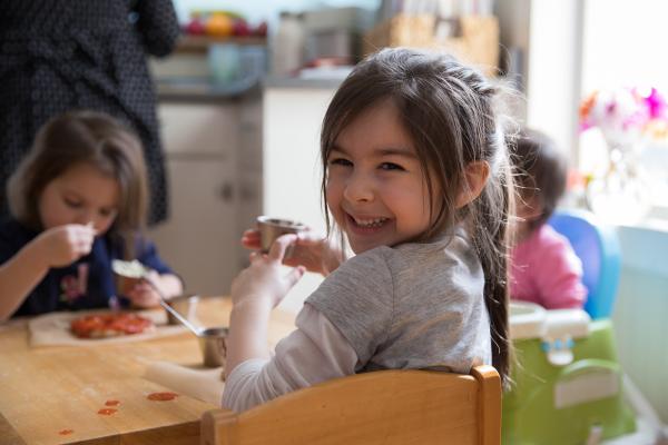 Three young children sit around a table at a childcare center