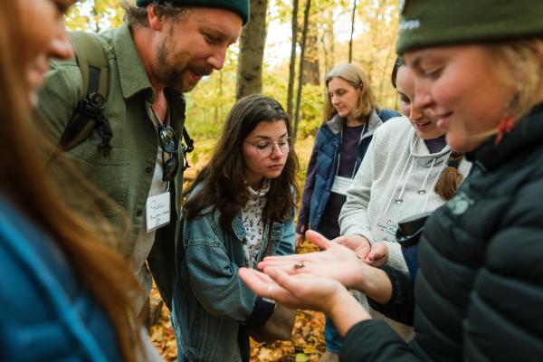 teachers in the forest observing a small object in palm of instructor