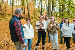 ABCs of Farm Based Education participants stand in fall forest listening to educator Jed Norris