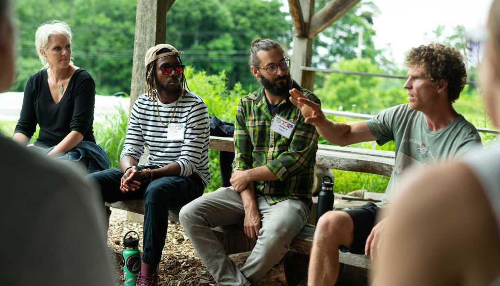 Educators sit under an outdoor pavilion in a garden