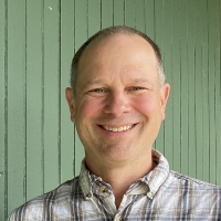 Rob Hunter in white checked shirt, smiling, close cropped hair