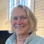 Woman with short, light blonde hair smiles at the camera in an indoor setting.