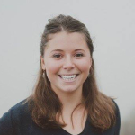 Nicole Green, medium length brown hair pulled back, smiling, v-neck dark blue sweater.